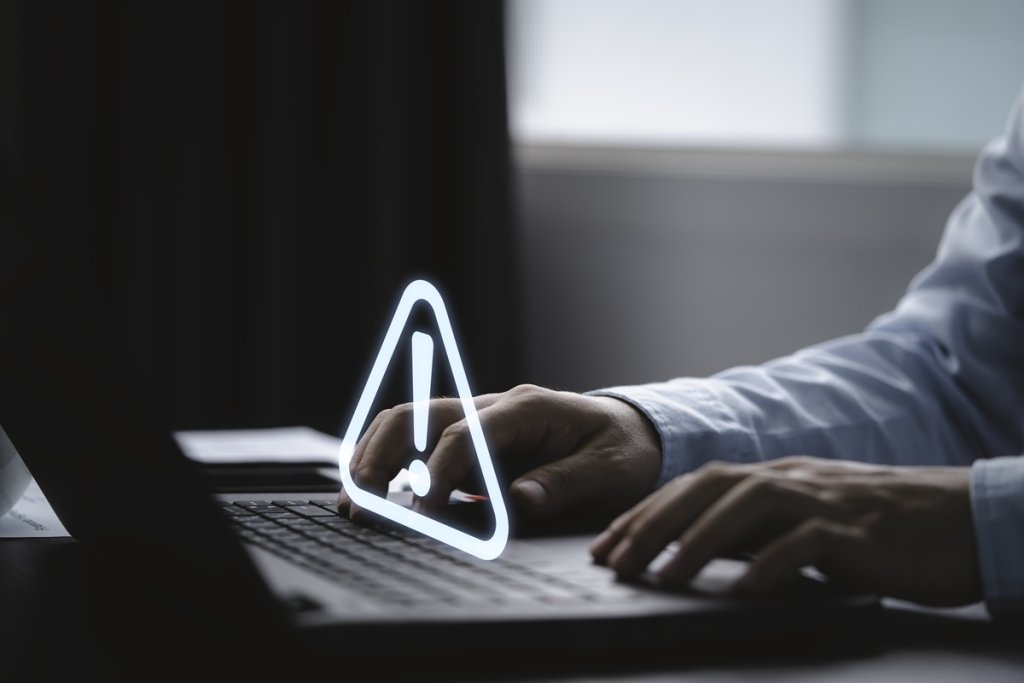 Businessman using computer laptop with triangle caution warning